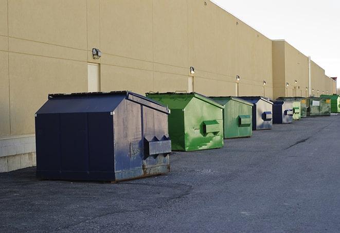 construction workers throw waste into a dumpster behind a building in Arrington